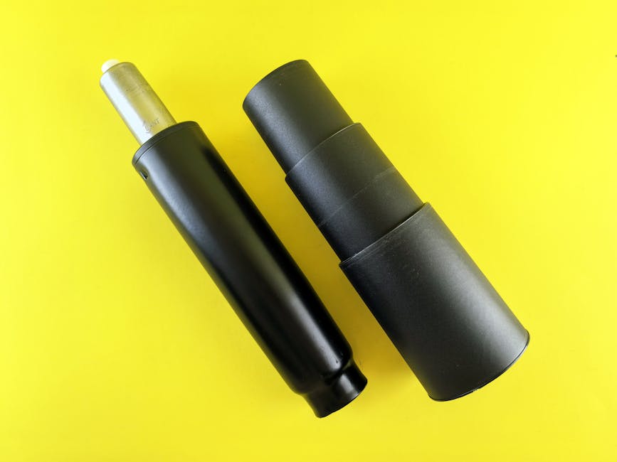 Two black gas lift cylinders for office chairs displayed on a bright yellow background.