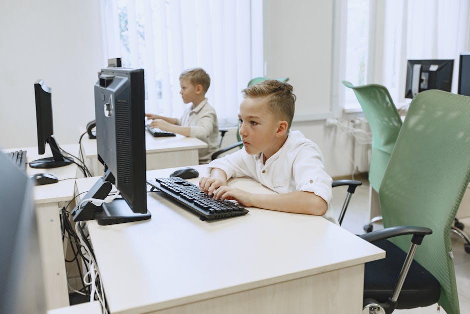 Two young boys focused on computers in a bright, modern classroom setting.