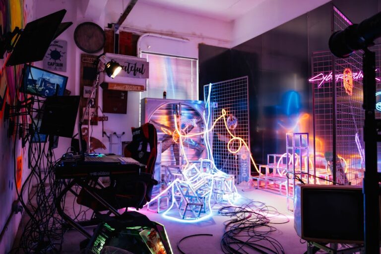 Colorful studio filled with neon lights, cables, and electronic equipment creating a futuristic ambiance.