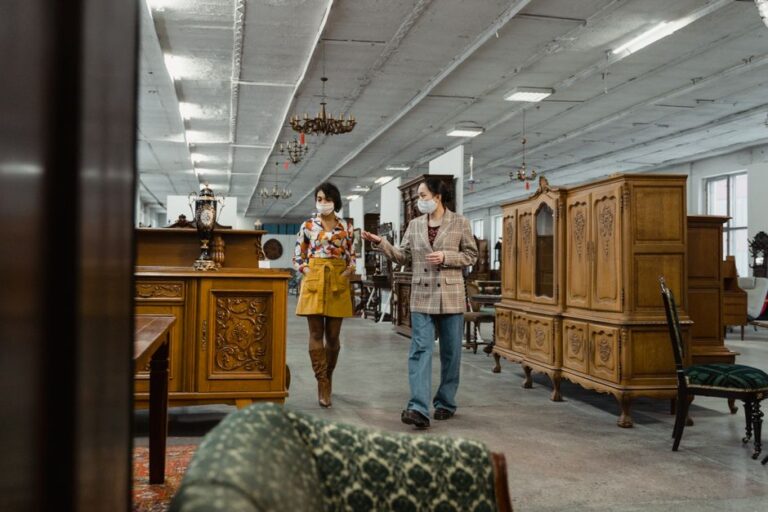 two adults in masks browse antique furniture in a stylish vi