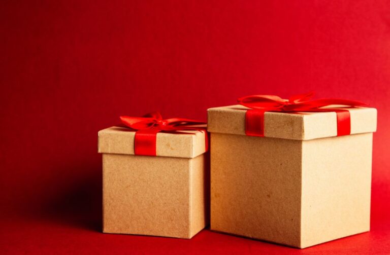 two gift boxes with red ribbons on a vibrant red background